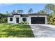 Charming single-story home featuring a black garage door, modern design, and a neatly landscaped front yard at 14009 Daniels Ave, Port Charlotte, FL 33953