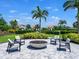 Outdoor fire pit with comfortable lounge chairs, palm trees, and neighborhood homes in the background at 15037 Montello Way, Lakewood Ranch, FL 34211