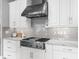 Modern kitchen with stainless steel hood, gas cooktop, quartz countertops, and subway tile backsplash at 15037 Montello Way, Lakewood Ranch, FL 34211