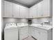 Bright laundry room with white cabinetry, sink and modern washer and dryer at 15037 Montello Way, Lakewood Ranch, FL 34211