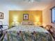 Warm bedroom with a floral bedspread, matching lamps, and a bright yellow accent wall with tropical art at 1526 Mission Hills Blvd # 18B, Clearwater, FL 33759