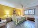 Bright bedroom features a floral-patterned bedspread, ceiling fan, and warm, inviting yellow wall paint at 1526 Mission Hills Blvd # 18B, Clearwater, FL 33759