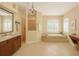 An elegant bathroom featuring a soaking tub, glass shower, and sophisticated vanity with decorative lighting at 15518 29Th E St, Parrish, FL 34219