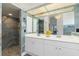 Bright bathroom with double vanity, decorative mirror, and a tiled shower with dual shower heads at 17343 Cayo Ln, Punta Gorda, FL 33955
