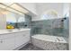 Bathroom featuring double sinks, garden tub with mosaic tile, and unique arched window at 17343 Cayo Ln, Punta Gorda, FL 33955