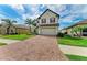 Inviting two-story home featuring a brick driveway, lush lawn, and manicured landscaping at 2084 La Palma Ave, Port Charlotte, FL 33953