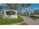 Welcoming Calusa Lakes community entrance with lush landscaping and palm trees under a bright blue sky at 2115 Timucua Trl, Nokomis, FL 34275
