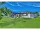 Backyard showing in-ground pool with screened in enclosure, beautiful green lawn, and white exterior of home at 22 Medalist Cir, Rotonda West, FL 33947