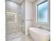 Modern bathroom with walk-in shower, stand-alone tub, and a frosted window at 22 Medalist Cir, Rotonda West, FL 33947