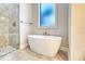 This modern bathroom features a walk-in shower, stand-alone tub, frosted window and gray tiling at 22 Medalist Cir, Rotonda West, FL 33947