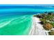 Stunning aerial view of a serene beach with clear, shallow waters and lush coastal vegetation at 225 Hourglass Way # 101, Sarasota, FL 34242