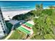 Aerial shot of a shuffleboard court next to a sandy beach, lush trees, and the ocean in the background at 225 Hourglass Way # 101, Sarasota, FL 34242