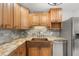 Kitchen featuring wooden cabinets, granite countertops, copper sink, stainless steel appliances, and tiled backsplash at 2751 71St E Dr, Sarasota, FL 34243