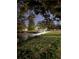 Evening shot of a gazebo sitting on a pond with lights, and a grassy hill with trees in the background at 3698 Glen Oaks Manor Dr, Sarasota, FL 34232