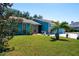 Teal-colored home with a well-kept lawn, accented by a small palm tree and vibrant flowers at 4219 Berkshire Dr, Sarasota, FL 34241