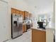 Well-lit kitchen featuring stainless steel appliances, wood cabinets, and white tile flooring at 4262 70Th Street E Cir, Palmetto, FL 34221