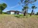 New home featuring a spacious lawn with young palm trees and grass and an exterior patio space at 5115 Foxhall Rd, North Port, FL 34288