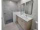 Bathroom featuring double sink vanity, modern fixtures, walk-in shower with marble tiling, and pebbled shower floor at 5115 Foxhall Rd, North Port, FL 34288