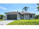 Charming single-story home featuring a well-maintained lawn, gray exterior paint, and a dark brown two-car garage door at 5115 Foxhall Rd, North Port, FL 34288