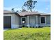 Close-up of a charming single-story home featuring a well-maintained lawn, gray exterior paint, and a white front door at 5115 Foxhall Rd, North Port, FL 34288