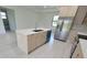 Open kitchen featuring stainless steel appliances, an island with a sink, light wood cabinets, and quartz countertops at 5115 Foxhall Rd, North Port, FL 34288