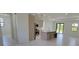 Bright open-concept living room with sleek flooring connects to a modern kitchen featuring an island and stainless appliances at 5115 Foxhall Rd, North Port, FL 34288