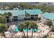 Aerial view of community pool, palm trees, and residential buildings, showcasing a resort-style living at 5631 Midnight Pass Rd # 1007, Sarasota, FL 34242