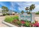 Welcoming White Sands Village sign with lush landscaping and palm trees under a bright blue sky at 5631 Midnight Pass Rd # 1007, Sarasota, FL 34242