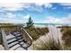 Stunning beach view with a wooden walkway leading to the white sandy shore and tranquil, turquoise ocean waters at 565 Sutton Place, Longboat Key, FL 34228