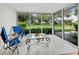 Bright sun room featuring tile floors, a glass table, and sliding glass windows with views of the garden at 565 Sutton Place, Longboat Key, FL 34228