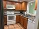 Functional kitchen featuring a stainless-steel sink, white appliances, and a window providing natural light at 5657 Westwind Ln, Sarasota, FL 34231