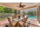 Covered patio with a dining table, ceiling fan, and screened enclosure overlooking the pool and backyard at 6620 Saint James Xing, University Park, FL 34201