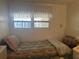 Bedroom with window, bed with patterned comforter, and white curtain at 6882 Holo Ct, North Port, FL 34287