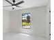 Bright bedroom with a ceiling fan, large window overlooking the backyard, and white tile floors at 7116 Quarry St, Englewood, FL 34224