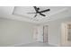 Primary bedroom with tray ceiling, ceiling fan, and view to en-suite bathroom at 7116 Quarry St, Englewood, FL 34224