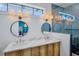 Modern bathroom with dual sinks, wood cabinets, marble counters, and custom lighting at 723 S Blvd Of The Presidents, Sarasota, FL 34236
