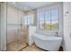 Modern bathroom featuring a glass enclosed shower, soaking tub, and a large window at 723 S Blvd Of The Presidents, Sarasota, FL 34236