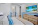 Comfortable bedroom with a light blue accent wall, TV, woven wood dresser, and adjacent bathroom at 723 S Blvd Of The Presidents, Sarasota, FL 34236