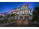Beautiful three-story home at twilight, featuring a brick driveway and three-car garage at 723 S Blvd Of The Presidents, Sarasota, FL 34236