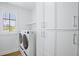 A well-lit laundry room with modern washer, dryer, and ample storage cabinets at 723 S Blvd Of The Presidents, Sarasota, FL 34236