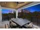 Outdoor patio with black metal railings, wood ceiling, fan and outdoor seating for 6 at dusk at 723 S Blvd Of The Presidents, Sarasota, FL 34236
