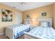 Cozy bedroom featuring two twin beds with matching seashell bedding and bright tropical artwork at 7639 Fairway Woods Dr # 605, Sarasota, FL 34238