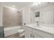 Bright bathroom featuring a tub with tiled surround, white vanity, and a large mirror at 9725 Last Light Gln, Parrish, FL 34219