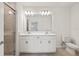 Bright bathroom featuring a double sink vanity with stone countertops, a toilet, and a glass-enclosed shower at 9725 Last Light Gln, Parrish, FL 34219