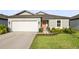 Charming single-story home with a manicured lawn, two-car garage, and a vibrant coral-colored front door at 9725 Last Light Gln, Parrish, FL 34219