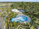 Aerial view of community splashpad, clubhouse, parking, and manicured landscaping with mature trees at 9725 Last Light Gln, Parrish, FL 34219