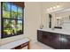 Well-lit bathroom offers a serene space with a dark wood vanity and lovely window view at 10816 O Meara Way, Englewood, FL 34223