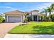 Beautifully landscaped gray home features a tile roof, two car garage, and a manicured lawn at 10816 O Meara Way, Englewood, FL 34223