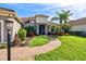 Well-manicured front yard featuring lush green lawn, colorful flowerbeds, and a charming brick walkway at 10816 O Meara Way, Englewood, FL 34223