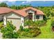Charming single-story home with a well-manicured lawn, lush garden beds, and a terracotta tile roof at 1358 Cielo Ct, North Venice, FL 34275